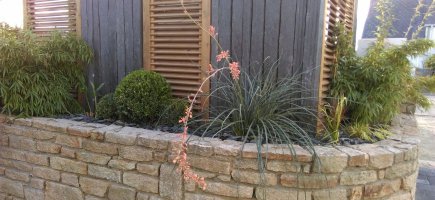 Le mélange du granit sur le muret, des piquets de schiste et du bois traité marron Le mélange du granit sur le muret, des piquets de schiste et du bois traité marron